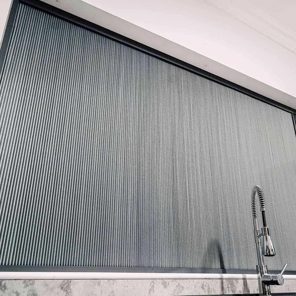 Close-up of BlindScreen® charcoal pleated fabric on a kitchen window