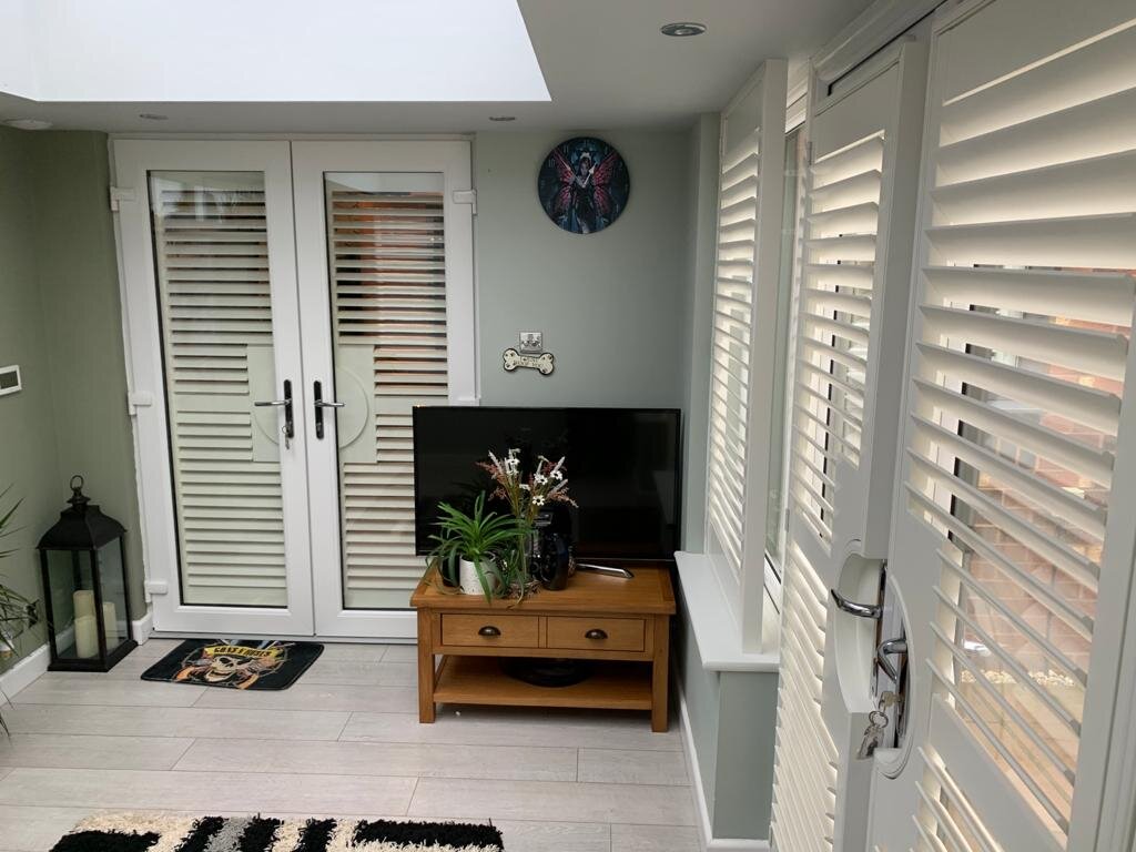 White plantation shutters on uPVC French doors with circular cut-outs around the handles — a typical survey detail.