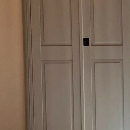 Close detail of painted solid panel shutters showing recessed panel joinery and a black ring pull