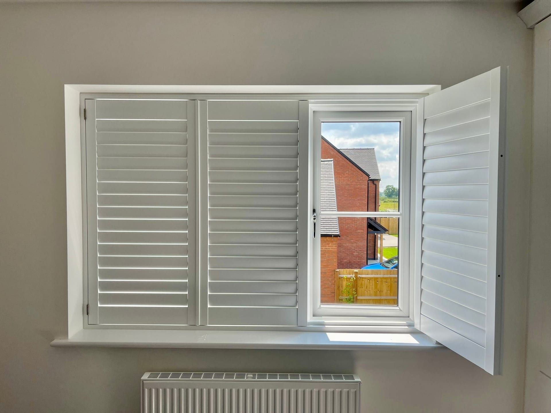 Hinged plantation shutter panel swung fully open so the window behind can be opened — Shutter Envy install in Leicestershire