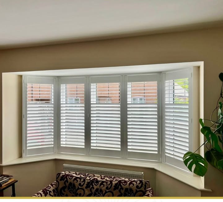 White shutters across a bay in a Leicestershire living room, louvres open for daylight