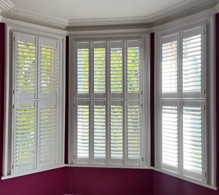 Same bay with louvres open across the white tier-on-tier panels against plum walls